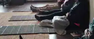 Partecipanti seduti a terra con le gambe distese su tappetini pieghevoli durante una sessione di mindfulness, tecniche di meditazione Bodhi Vipal al Centro Zorba Il Buddha.