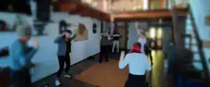 Gruppo di persone in piedi in cerchio sul pavimento in legno che eseguono movimenti con le braccia sollevate durante una sessione di depurazione sottile in un ritiro di meditazione attiva, tecniche di meditazione Bodhi Vipal al Centro Zorba Il Buddha.