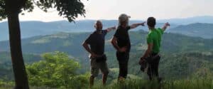 Tre uomini su una collina panoramica indicano l'orizzonte durante un ritiro di meditazione all'aperto, Centro meditazione Zorba Il Buddha, tecniche di meditazione Bodhi Vipal.