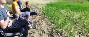 Gruppo di persone sedute all'aperto che praticano tecniche di meditazione Bodhi Vipal con le mani sul cuore durante un ritiro sciamanico.