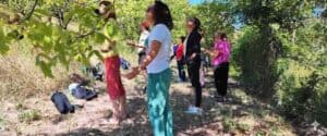 Un gruppo di persone pratica il risveglio energetico in piedi nel bosco, con le braccia aperte e il volto rivolto verso l'alto, durante un ritiro al Centro Zorba il Buddha.