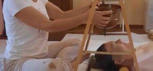 Insegnante Maria Cordino che regola la vasca in rame per il trattamento ayurvedico Shirodhara su una persona distesa a terra, durante un ritiro di Ayurveda al Centro meditazione Zorba Il Buddha.